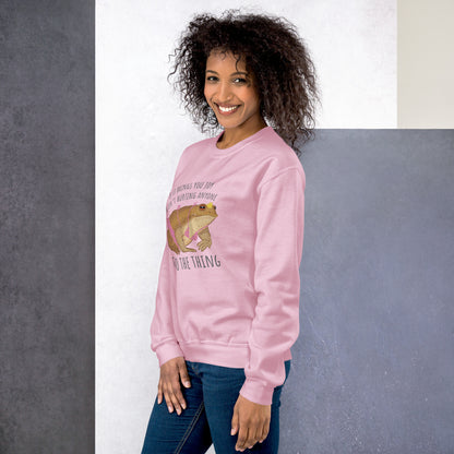 Woman wearing a pink sweatshirt with a  toad graphic and text, standing against a plain background